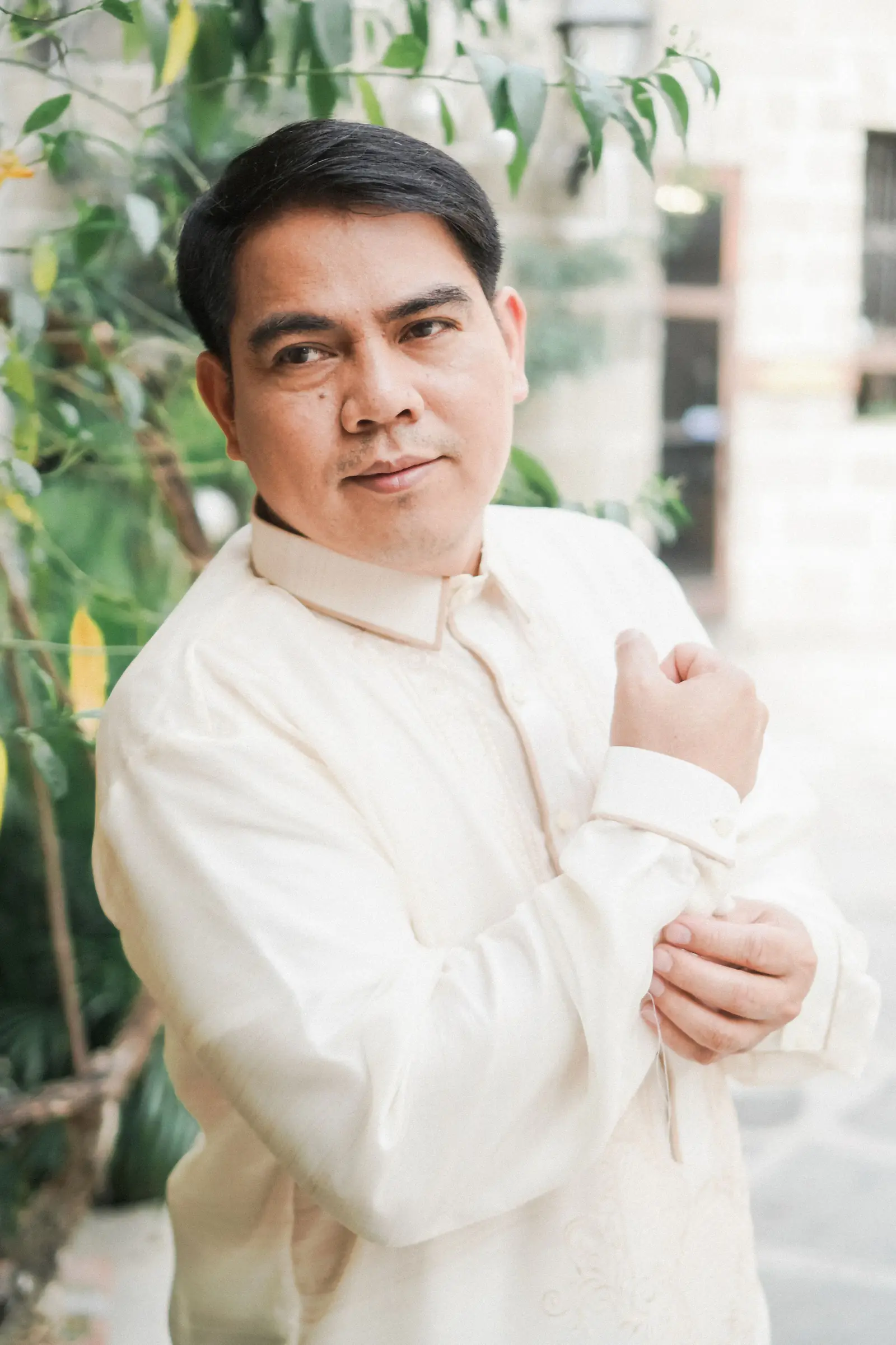 A man adjusting the sleeve of his barong tagalog.