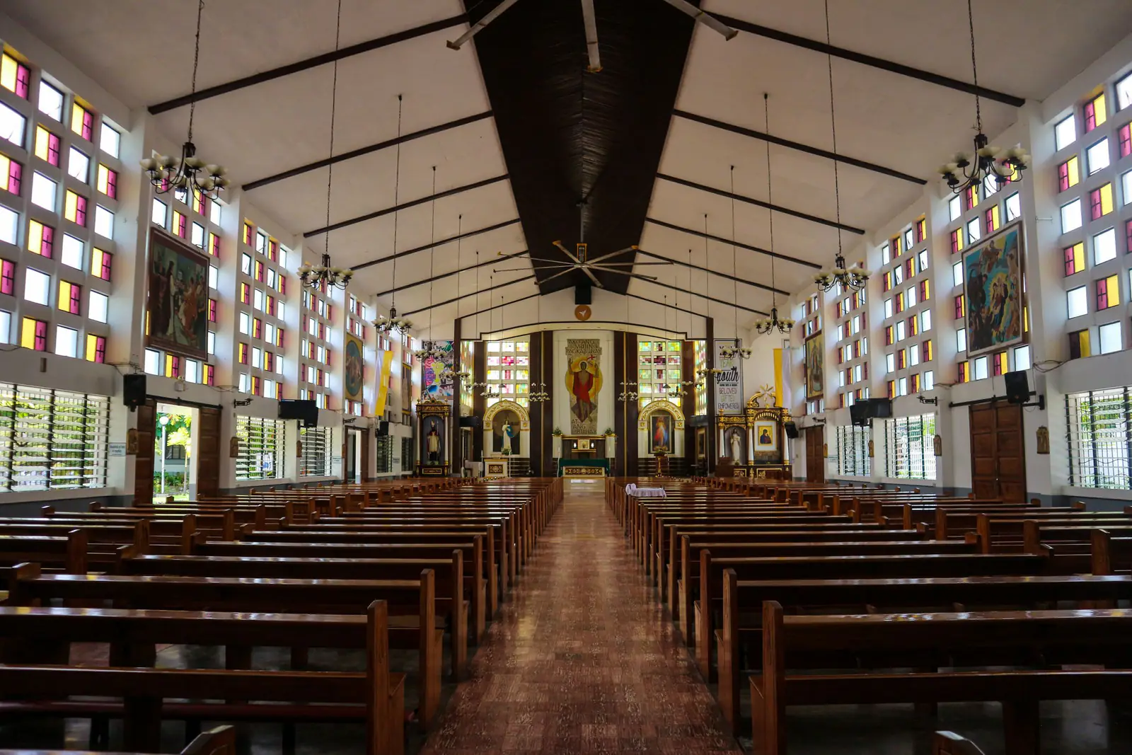 Church interior with pews and stained glass windows.