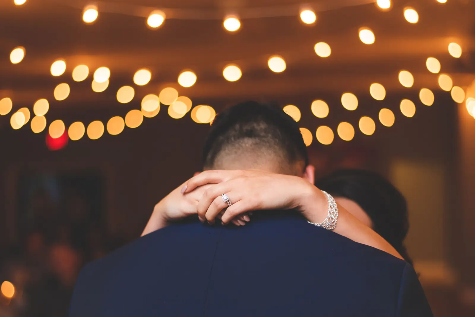 A couple dancing under warm string lights.