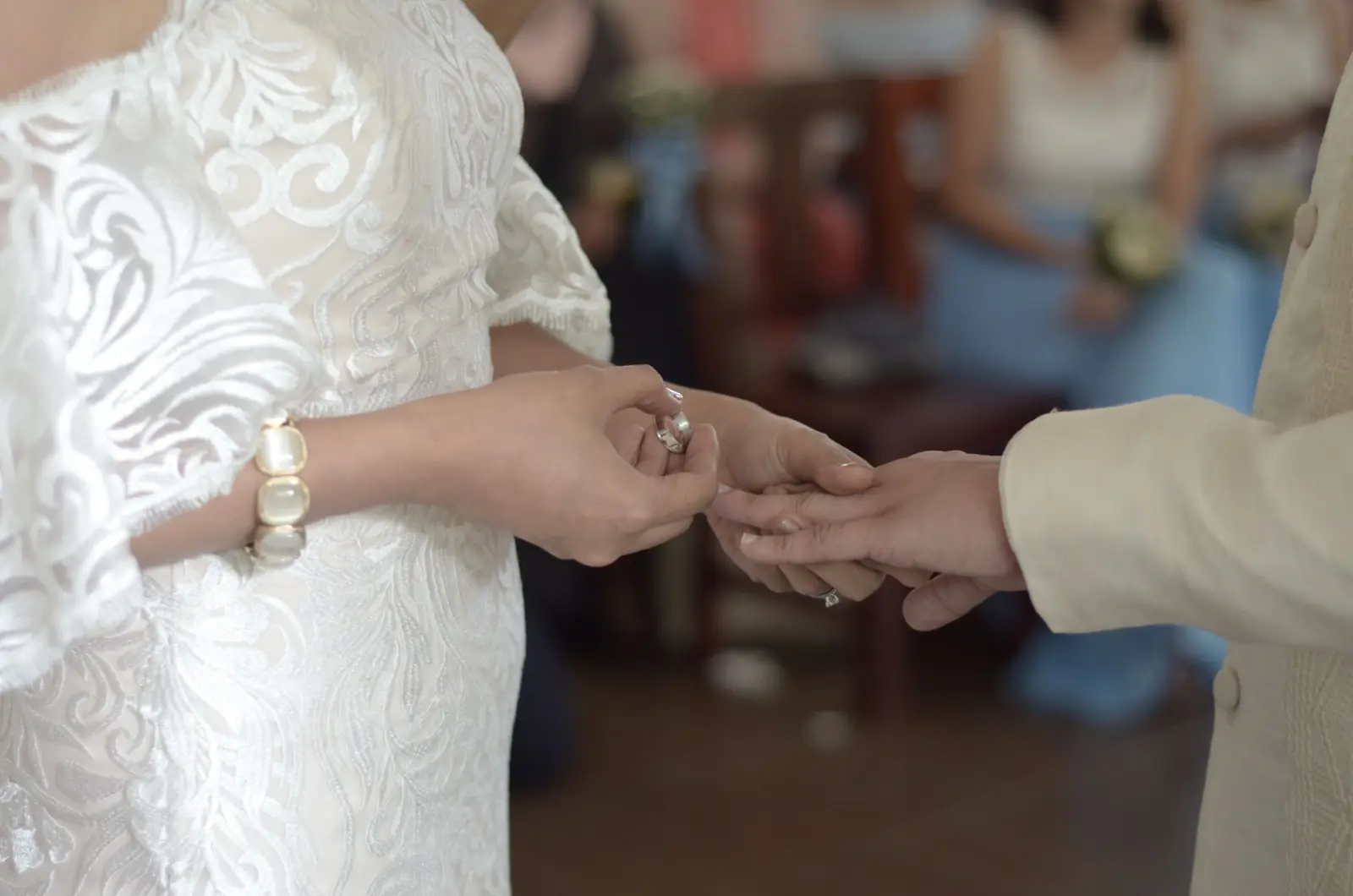 A close-up of a bride and groom exchanging rings during a wedding ceremony indoors.